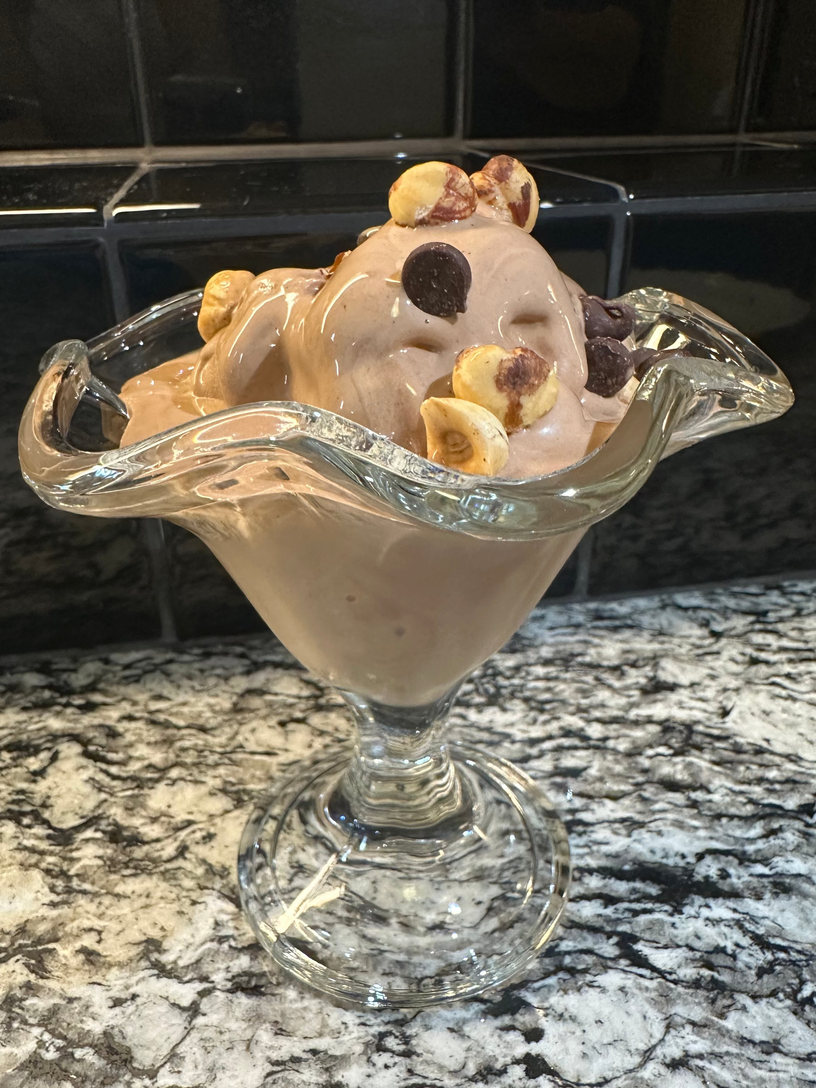 Glass dessert bowl with ice cream and cookies on a marble surface